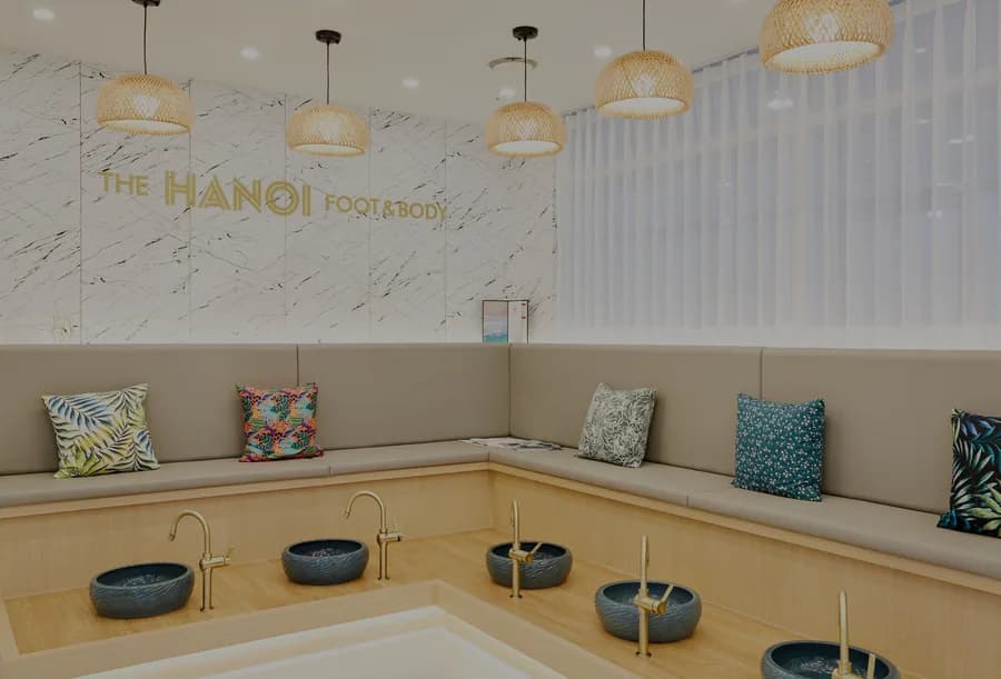 매장 족욕 라운지 — 벽면 THE HANOI FOOT&BODY 금색 사인과 원목 벤치